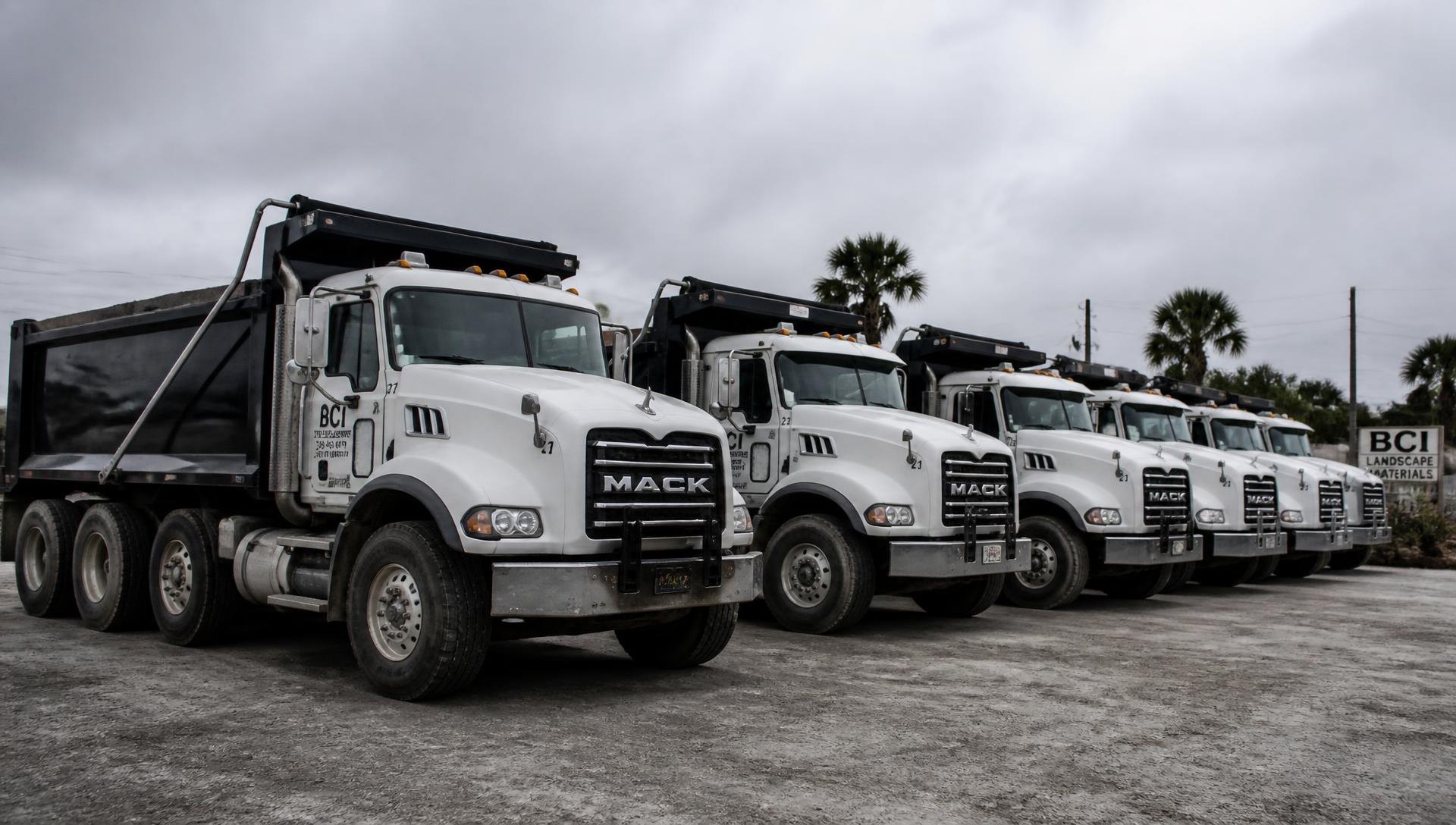 Row of white dump trucks parked at the Pasco's Ontime Hauling yard